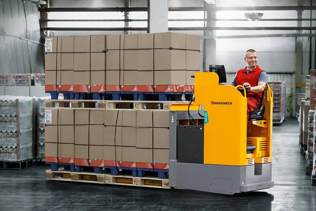 Elektryczny wózek paletowy Jungheinrich z operatorem podczas transportu palet w magazynie