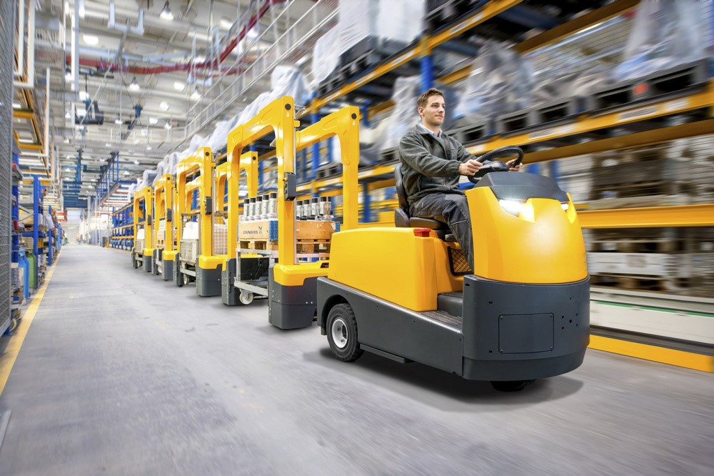 Elektryczny ciągnik Jungheinrich transportuje wózki kompletacyjne w magazynie